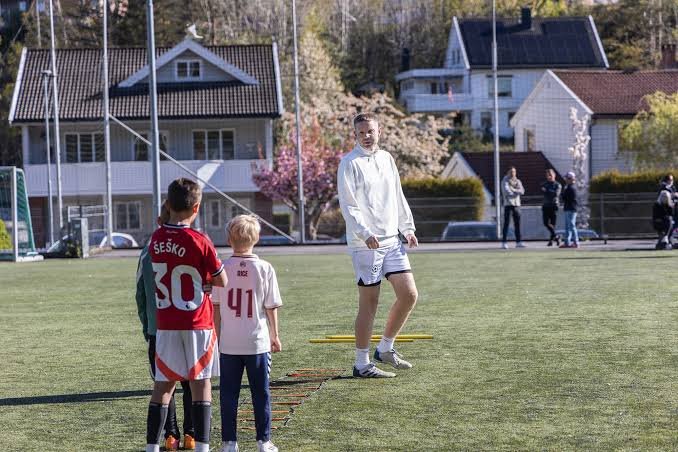 Trener i samtale med to unge spillere på banen